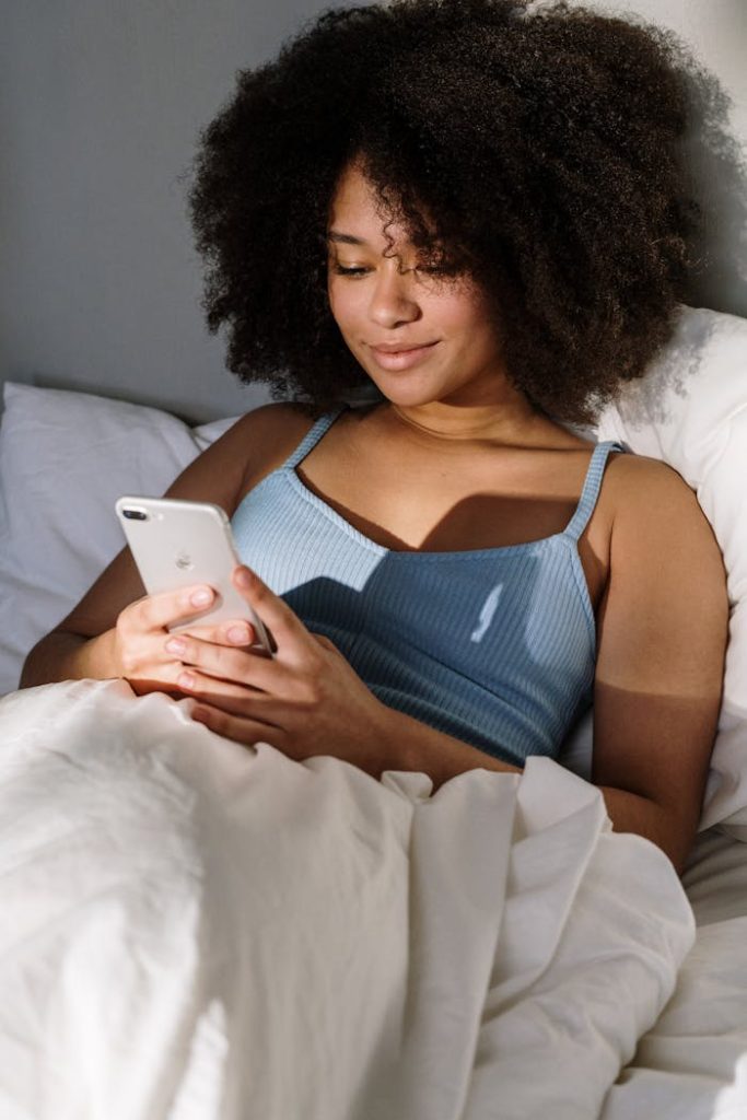 pexels-photo-4046303 African American woman enjoying a cozy morning in bed, using a smartphone.