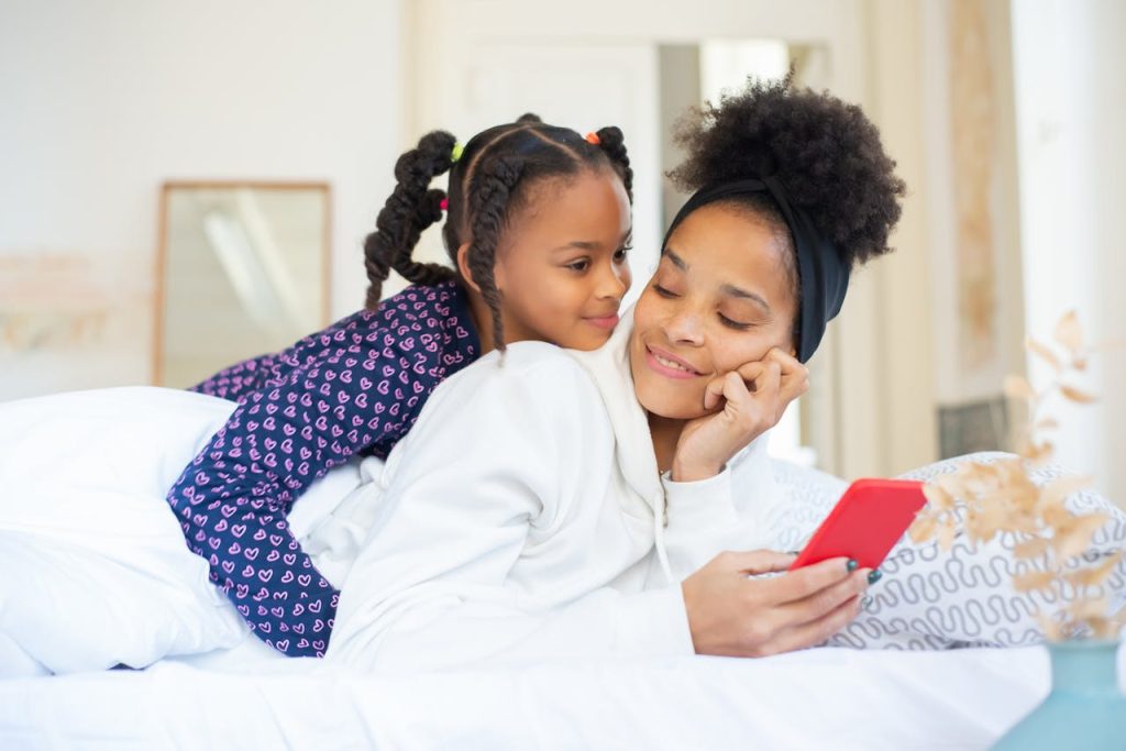 pexels-photo-6948092 A heartwarming moment between a mother and daughter embracing while using a smartphone indoors.